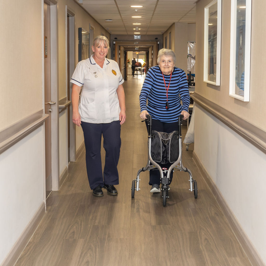 Physiotherapist walking with a patient in residential home.