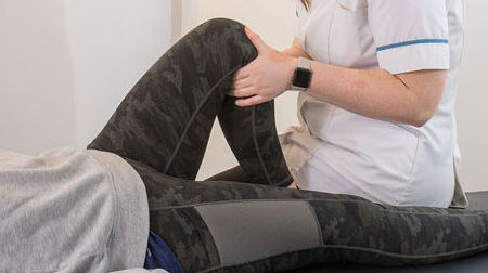 Houlbrook physio therapist assessing a patients knee, their hands on their knee to test strength and range